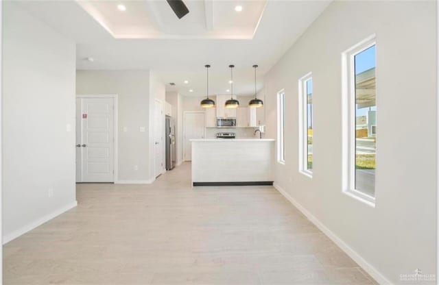 kitchen featuring a tray ceiling, white cabinetry, pendant lighting, and appliances with stainless steel finishes