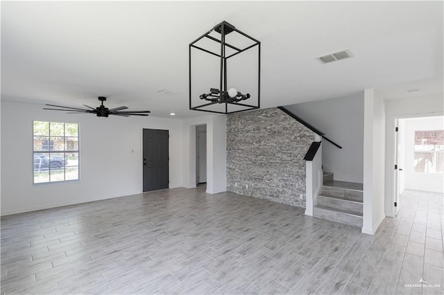 unfurnished living room featuring light wood-style floors, a wealth of natural light, visible vents, and stairway