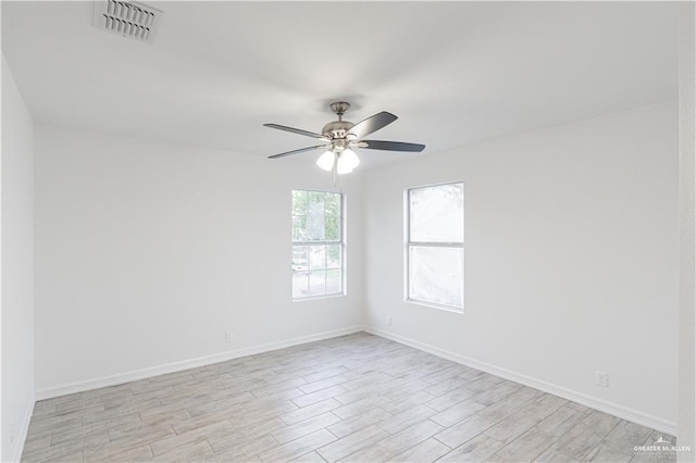 empty room featuring light wood-style floors, visible vents, baseboards, and ceiling fan