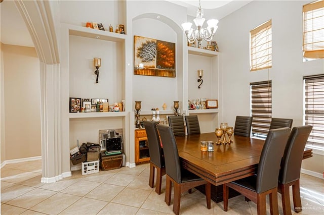 dining room with a wealth of natural light, light tile patterned flooring, a high ceiling, and an inviting chandelier