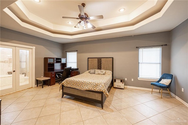 tiled bedroom with french doors, a tray ceiling, ensuite bath, and ceiling fan