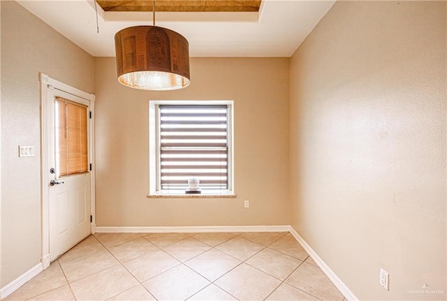 empty room featuring light tile patterned floors and a raised ceiling