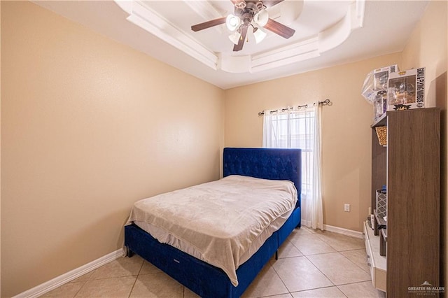 tiled bedroom with a tray ceiling and ceiling fan