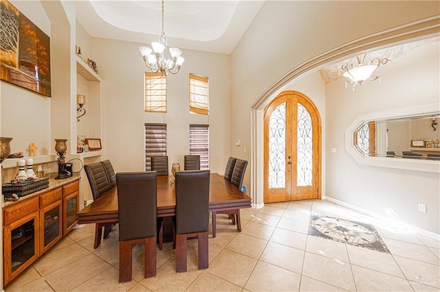 tiled dining room featuring french doors, a towering ceiling, and an inviting chandelier