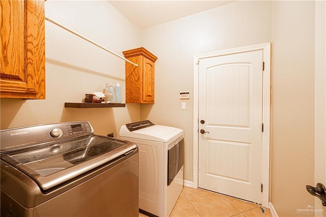 washroom featuring washer and dryer, light tile patterned floors, and cabinets