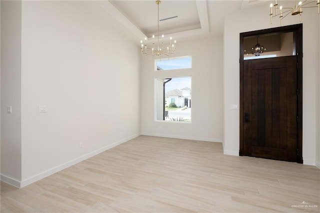 entryway with a chandelier, a raised ceiling, and light hardwood / wood-style flooring