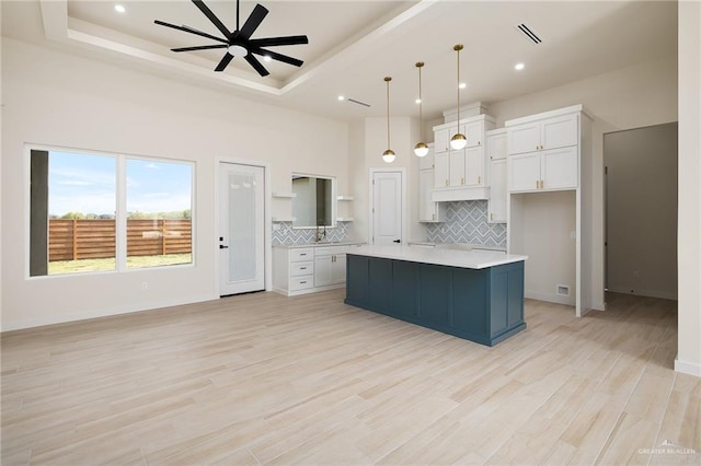 kitchen with white cabinetry, a kitchen island, pendant lighting, and light wood-type flooring