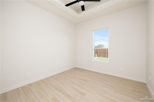 unfurnished room featuring light wood-type flooring, a raised ceiling, and ceiling fan