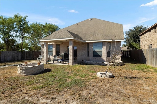 rear view of property featuring a patio area, a yard, and a fire pit