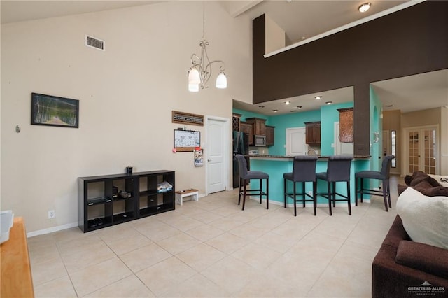 kitchen with black fridge, high vaulted ceiling, kitchen peninsula, a chandelier, and a kitchen bar