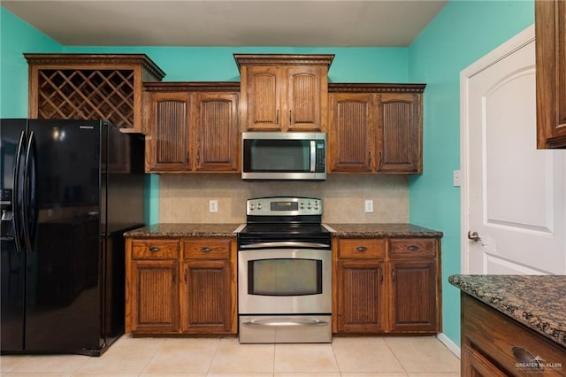 kitchen with light tile patterned flooring, appliances with stainless steel finishes, tasteful backsplash, and dark stone countertops