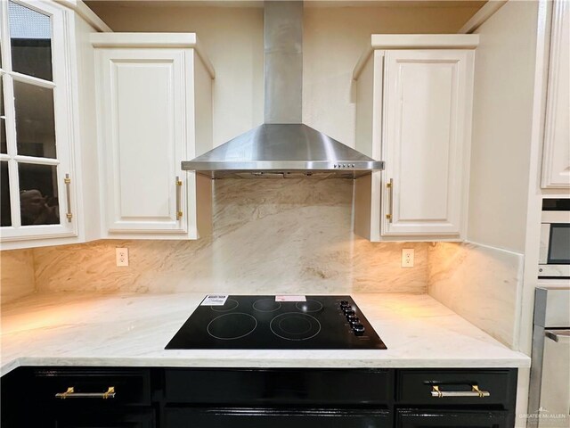 3106 Salvador Ave, Edinburg, TX 78539 - kitchen with wall chimney range hood, black electric cooktop, decorative backsplash, white cabinets, and dark cabinets