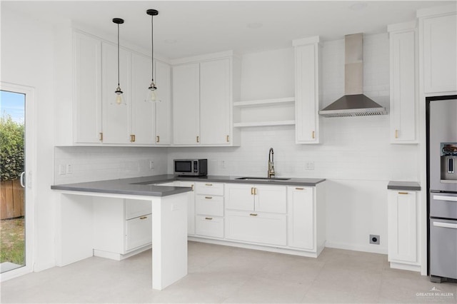 kitchen with pendant lighting, white cabinetry, wall chimney exhaust hood, and sink