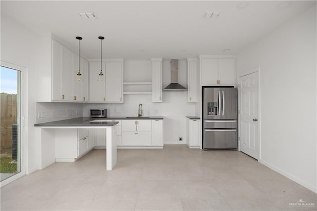 kitchen featuring white cabinets, wall chimney exhaust hood, decorative light fixtures, and appliances with stainless steel finishes