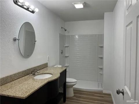 bathroom with hardwood / wood-style floors, vanity, toilet, and walk in shower