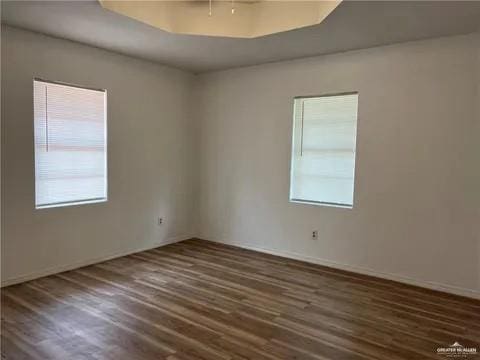 unfurnished room featuring dark hardwood / wood-style floors and a tray ceiling