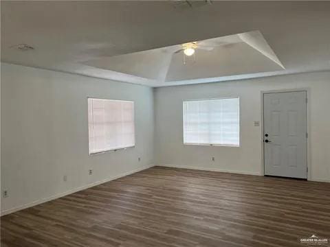 unfurnished room with dark hardwood / wood-style flooring, a raised ceiling, and ceiling fan