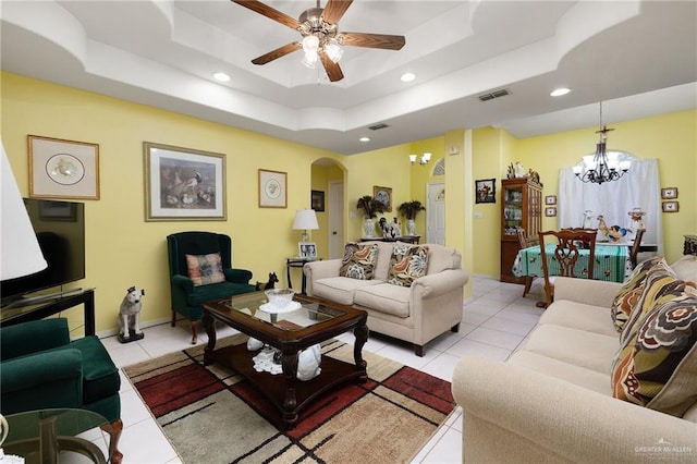 living room with light tile patterned floors, visible vents, a tray ceiling, recessed lighting, and arched walkways