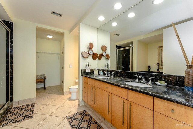 bathroom with tile patterned flooring, vanity, a shower with door, and toilet