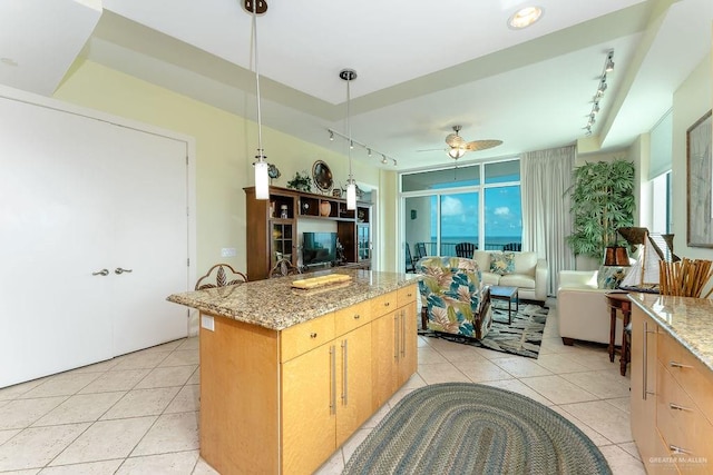 kitchen with ceiling fan, hanging light fixtures, rail lighting, and light stone counters