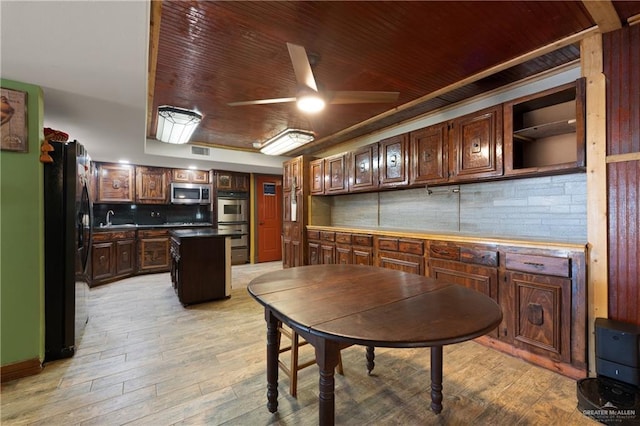 kitchen with appliances with stainless steel finishes, light wood-style flooring, a center island, ceiling fan, and a sink