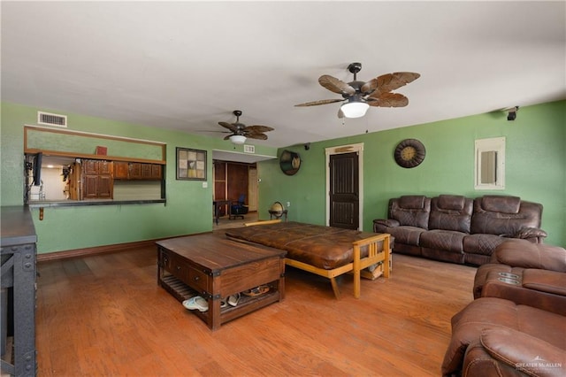 living area with visible vents, ceiling fan, and wood finished floors