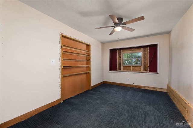 empty room with dark carpet, ceiling fan, and baseboards