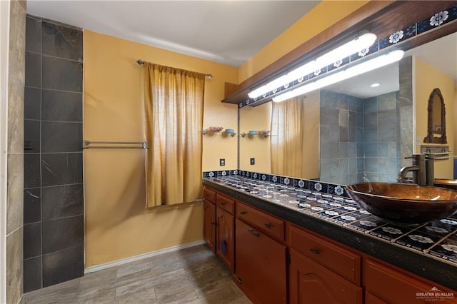 bathroom featuring double vanity, baseboards, and a sink