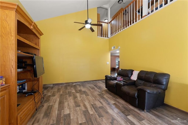 living room featuring dark wood-type flooring, high vaulted ceiling, baseboards, and a ceiling fan