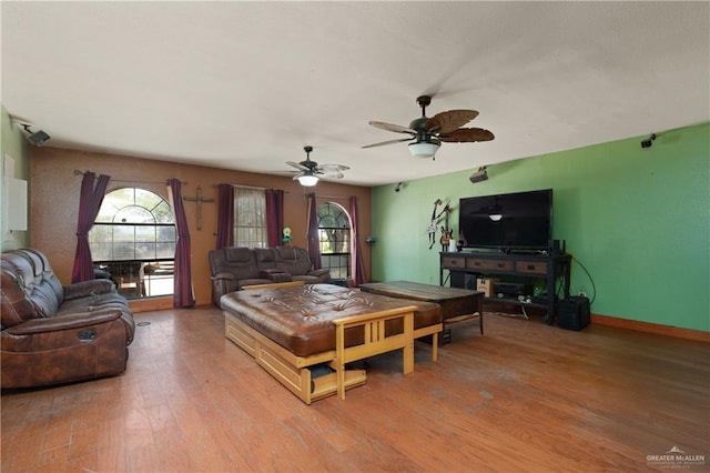 living room featuring ceiling fan, baseboards, wood finished floors, and a healthy amount of sunlight