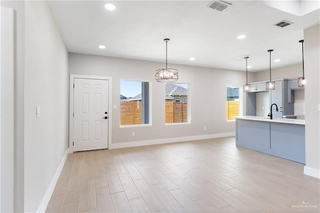 kitchen with light wood-type flooring, decorative light fixtures, and a wealth of natural light