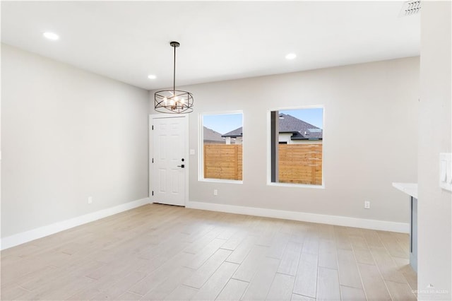 unfurnished room featuring light hardwood / wood-style floors and an inviting chandelier