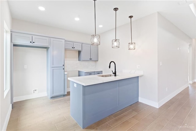 kitchen featuring pendant lighting, sink, light hardwood / wood-style flooring, tasteful backsplash, and kitchen peninsula