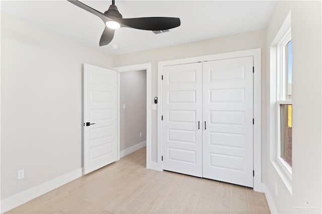 unfurnished bedroom featuring multiple windows, ceiling fan, a closet, and light hardwood / wood-style floors