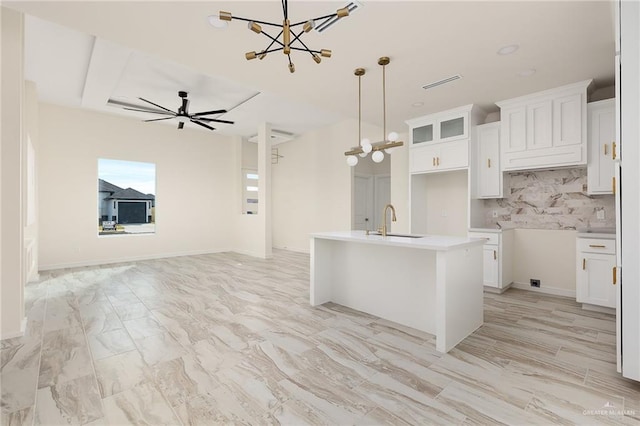 kitchen with decorative light fixtures, white cabinetry, a kitchen island with sink, and sink