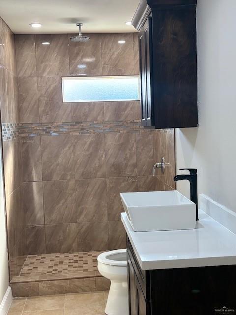 bathroom featuring vanity, tile patterned floors, toilet, and a tile shower