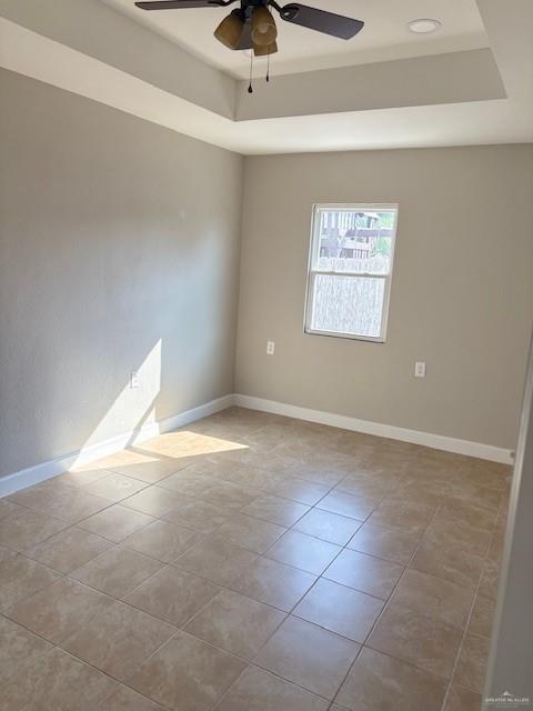 tiled spare room with a raised ceiling and ceiling fan