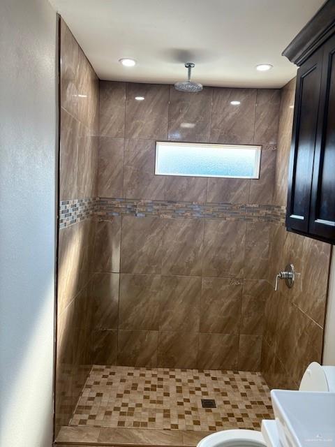 bathroom featuring tiled shower and toilet