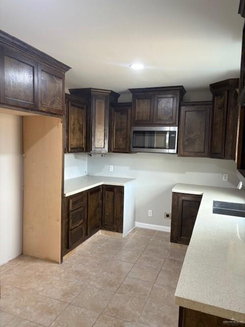 kitchen featuring dark brown cabinetry, sink, and light tile patterned floors