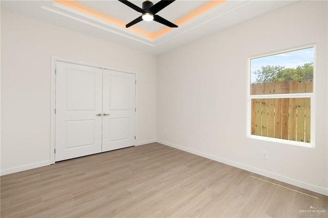 4909 Columbia Ave, Mcallen, TX 78504 - unfurnished bedroom with a tray ceiling, light wood-style flooring, baseboards, a closet, and ceiling fan