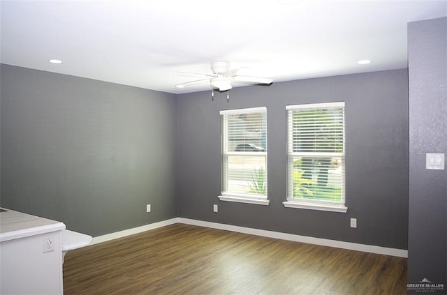 empty room with a wealth of natural light, ceiling fan, and dark wood-type flooring