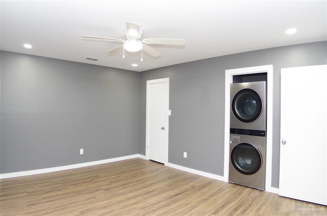 laundry area featuring light hardwood / wood-style floors, ceiling fan, and stacked washer / drying machine