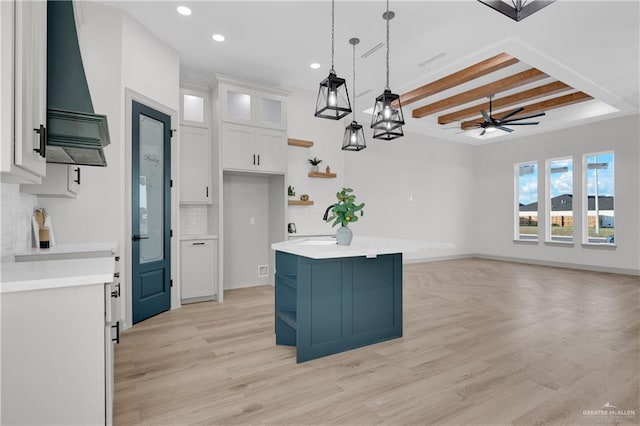 kitchen with light countertops, light wood-type flooring, open shelves, beamed ceiling, and decorative light fixtures