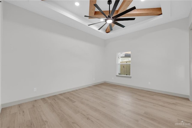 spare room featuring ceiling fan, baseboards, light wood-style flooring, and a tray ceiling