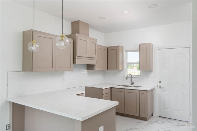 kitchen with kitchen peninsula, decorative backsplash, sink, and hanging light fixtures