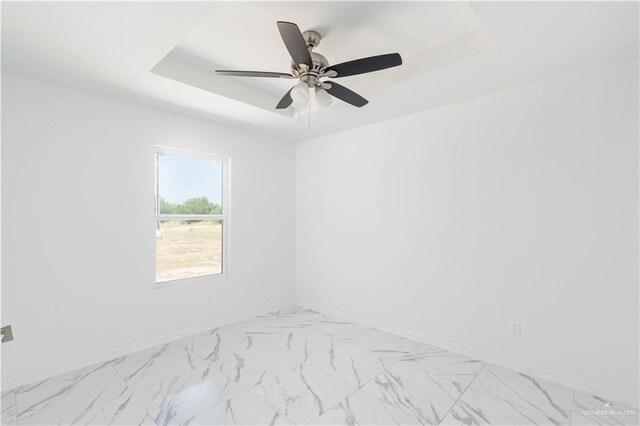 empty room featuring a tray ceiling and ceiling fan