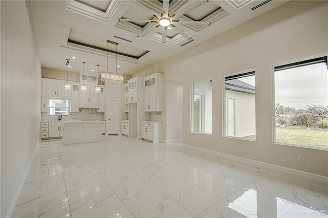 unfurnished living room with coffered ceiling, sink, a wealth of natural light, and a high ceiling