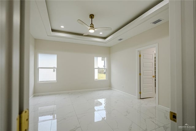 empty room featuring ceiling fan and a tray ceiling