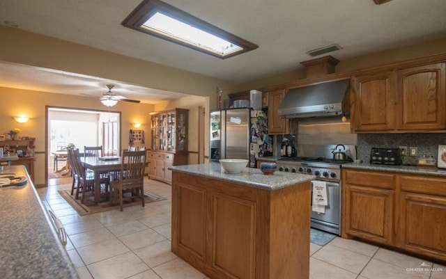 2517 E Mile 4th Rd, Mission, TX 78573 - kitchen with wall chimney exhaust hood, appliances with stainless steel finishes, brown cabinetry, light tile patterned floors, and backsplash