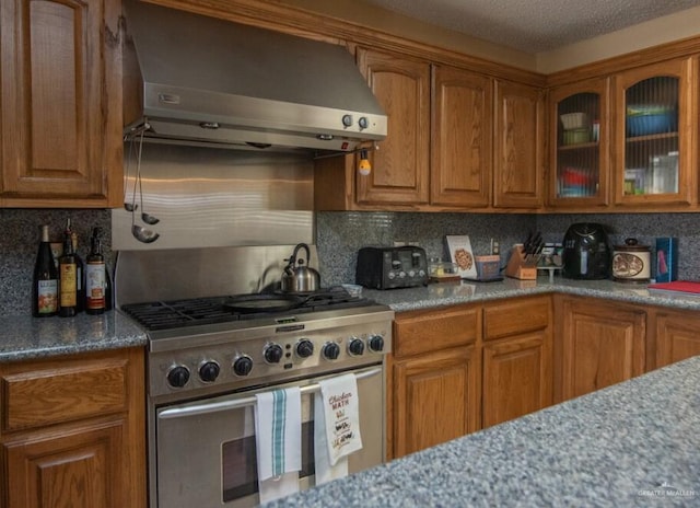 2517 E Mile 4th Rd, Mission, TX 78573 - kitchen featuring high end stove, wall chimney exhaust hood, brown cabinetry, and backsplash